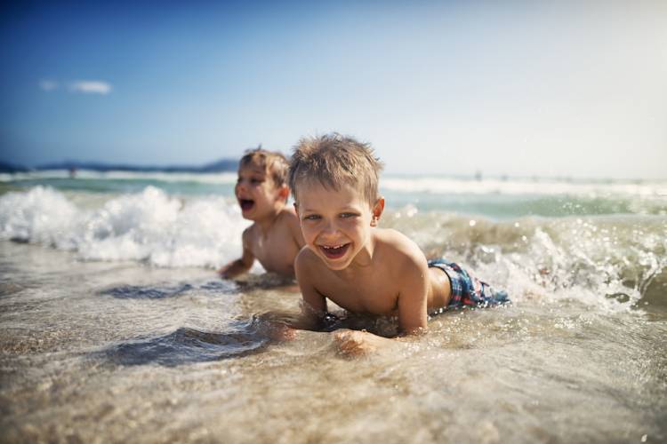 two young boys playing in the waves on the beach