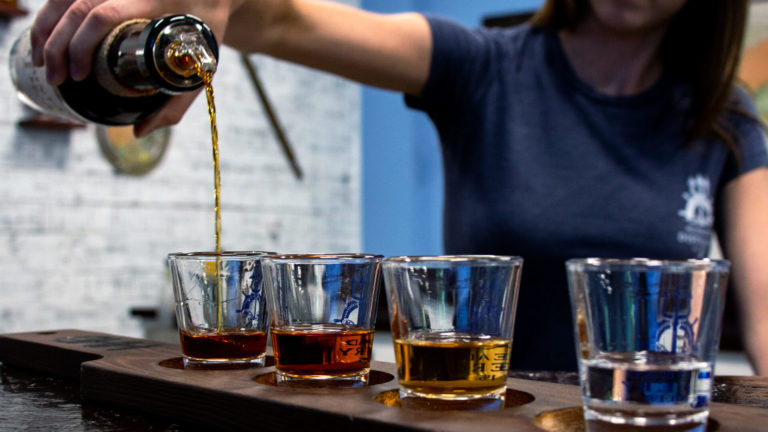 A woman pouring beer samples at a local distillery